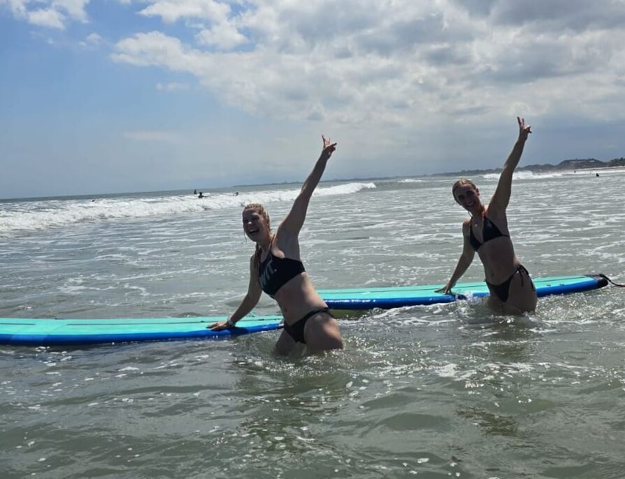 Kids surf lesson with instructor providing hands-on guidance